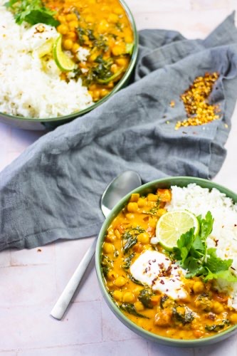 Two plates with rice and the delicious chickpea curry garnished with cilantro and lime