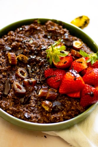 a close picture with the simple and healthy chocolate porridge garnished with dates and strawberries